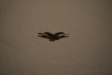 Silver coloured metal brooch depicting soaring eagle with pin at back