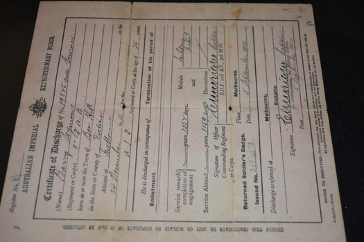 Pale pink coloured paper document with black writing and crest.