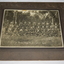 Black and white photograph mounted on dark grey cardboard depicting three rows of soldiers wearing bush hats and front row holding rifles