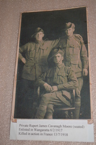 Reproduction copy of black and white portrait of three uniformed men two standing and one seated in front.