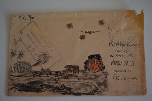 Cream paper envelope with drawing of war scene - cannon in front of hut and palm trees, ambulance in centre and bomb exploding below aircraft in sky.