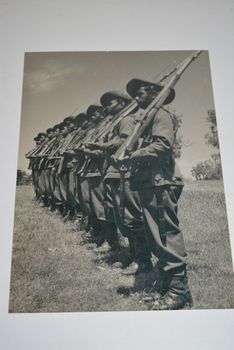 Black and white photograph of soldiers in single file on parade