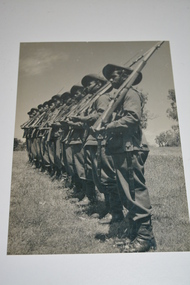Black and white photograph of soldiers in single file on parade