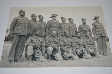 Black and white photograph of five soldiers kneeling in front of eight soldiers standing