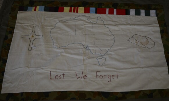 Handmade quilt with hand stitched map of Australia, a cross with metal Vietnam badge and a slouch hat on white cloth