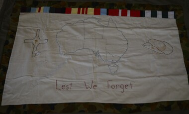 Handmade quilt with hand stitched map of Australia, a cross with metal Vietnam badge and a slouch hat on white cloth