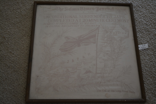Timber frame containing red and white silk scarf featuring newspaper headline 