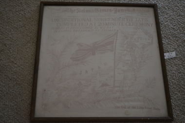 Timber frame containing red and white silk scarf featuring newspaper headline 