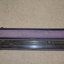 The long narrow case is fabric covered wood with felt fabric lining containing a long black laminate ruler with numerous white markings and numbers.  Top of the ruler is in three sections with the centre section movable by small gold metal knobs at either end.
 