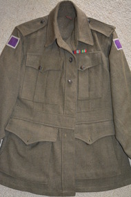 Khaki woollen jacket with shoulder epaulettes and four pockets with brass buttons attached.  