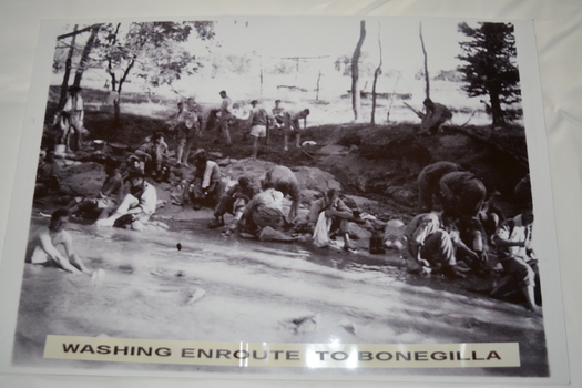 Group of soldiers in various stages  of dress in and on the bank of a river