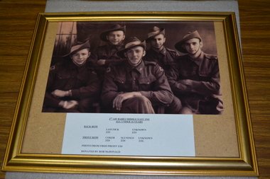Four soldiers wearing slouch hats sitting down posing for photograph with list of names below