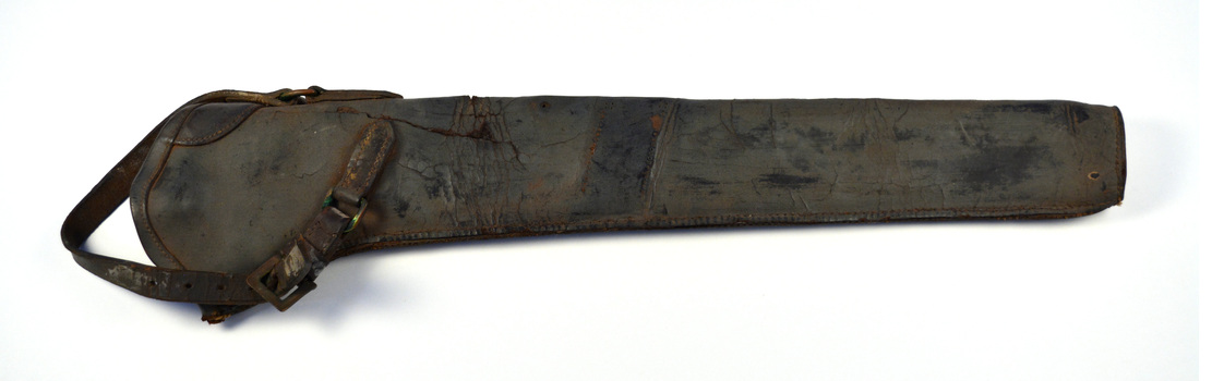 Long cylinder shape made from dark brown leather with leather strap and  brass buckle at the top of the bucket which attaches it to a saddle
