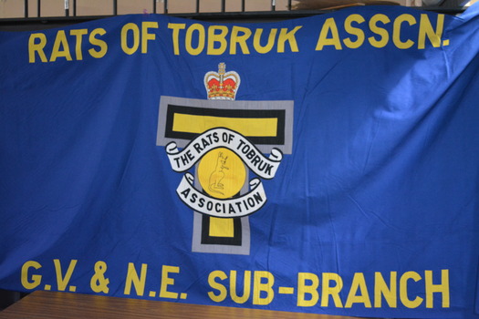 Large blue fabric banner with wording in yellow above and below emblem 