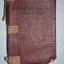 Burgundy colour imitation leather bound book with black imprint on cover held together with bandaids
