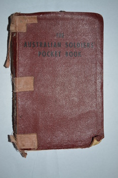 Burgundy colour imitation leather bound book with black imprint on cover held together with bandaids
