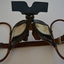 Black metal goggles with black plastic sun visor attached to circular brown cloth strapping