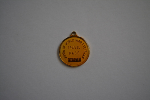 Round gold metal token with small loop attached at top