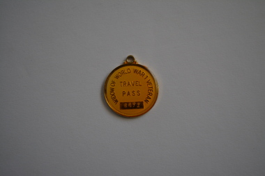 Round gold metal token with small loop attached at top
