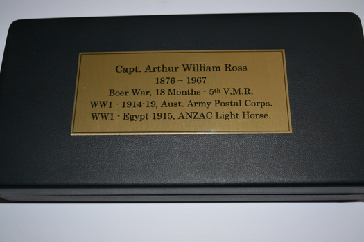 Medals contained in black covered box with gold coloured metal  plaque with black printing attached to lid.