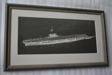 Framed black and white image of a ship with aircraft on deck at ship’s bow and stern.