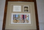 Brown frame containing beige mount housing black and white photograph and set of 8 medals