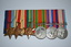 Six medals with multi coloured ribbons attached mounted on black felt with large pin attached at rear.  