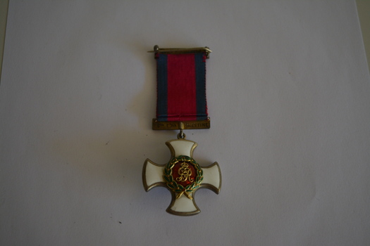 Cross shaped medal inlaid with white enamel.  In the centre is the imperial crown in gold upon a red enamelled background surrounded by a laurel wreath.  The reverse side depicts the royal cypher