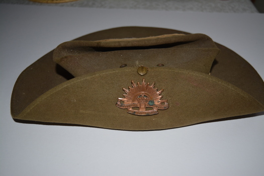 Khaki felt hat with rising star badge attached to brim turned up on right side.
