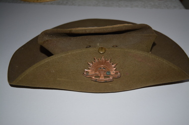 Khaki felt hat with rising star badge attached to brim turned up on right side.