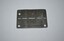 Dark grey rectangle shaped piece of metal with small hole in three of the four corners and narrow cut out slots across centre line stamped either side with letters and numbers.