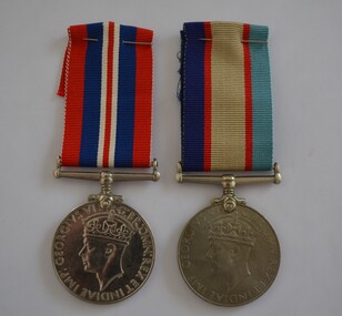Two round silver metal medals with striped ribbons attached