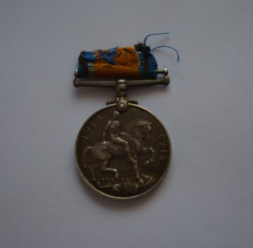 Round silver metal medal with remnants of blue and orange ribbon on attached clasp suspender bar. 