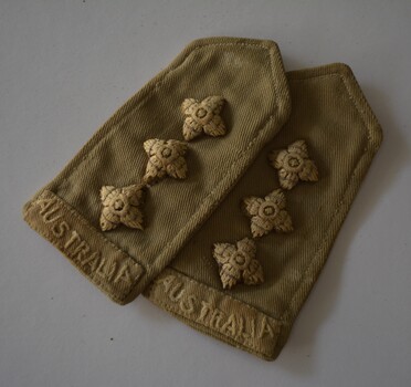 Two khaki fabric epaulettes each with three stars in a row and “Australia”stitched at one end