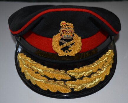 Dark blue fabric peaked cap featuring distinctive scarlet piping/band with badge and oak leaf embroidery on the peak.