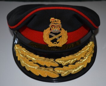 Dark blue fabric peaked cap featuring distinctive scarlet piping/band with badge and oak leaf embroidery on the peak.