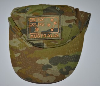 Camouflage fabric cap with vent holes, detachable badge above peaked brim.