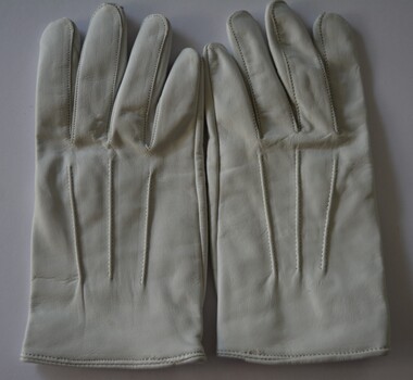 White leather gloves with three rows of stitching on top and snap fasteners attached.