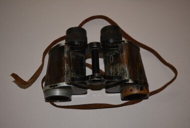 Black painted metal binoculars originally covered in black leather with little remaining.  The brown leather strap is well worn and missing stud fixing on right side.