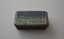 Rectangular tin with hinged lid containing small timber matches with wax heads. The tin is plain metal apart from two tone blue lid with lettering.   Underneath is a serrated patch used to strike the match.