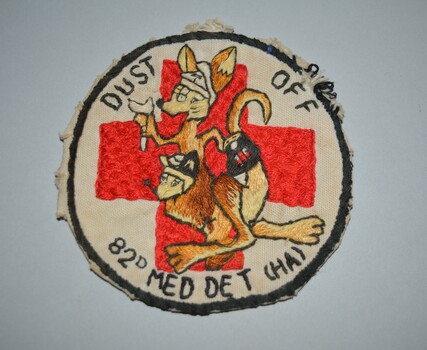 Embroided cotton patch consisting of a circle design featuring a kangaroo and joey superimposed over a large red cross on white background and thin black edging around the circle completes the design.