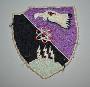 Embroided cotton patch of a shield design featuring a white buzzard's head set against a divided background of black and purple.