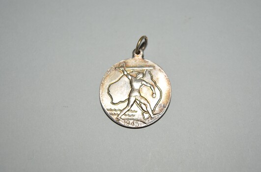 Circular medalet with suspension loop  depicts a knight with sword in front of an outline of Australia with 1945 at the bottom. The reverse shows a map of the southern hemisphere.
