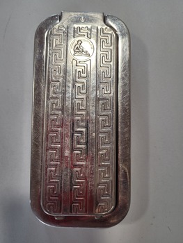 The case was a rigid rectangular chrome plated frame enclosed by two detachable lids; one lid carried a stone and the other a leather. The lids could not be interchanged. With a lid removed, oscillating a handle drove a shaft along the frame. In both directions pinions on the shaft engaged with racks on the case to rotate the shaft to either push the blade forward against the stone or drag it against the strop. It was easy to use, fast and safe. Sharpening was noisy as each change of direction rotated the blade to slap against stone or leather. The blade was about the size of a conventional disposable blade but was solid, hollow ground and not disposable, and it incorporated a safety guard.