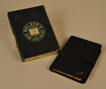 On the left is a box with the company logo center of the lid. The notebook has gold initials in the bottom right corner.