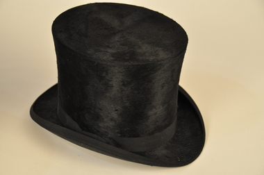 Black silky top hat on a white background. With a black ribbed silk ribbon. 