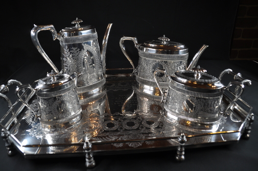 A set of four silver items consisting of coffee pot, tea pot, sugar pot, and milk jug, on a silver tray.