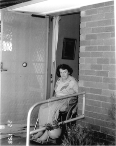 Laby in a wheelchair coming out her from door.