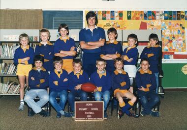 Two rows of boys in blue and yellow football shirts and a teacher centre rear.