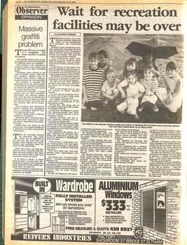 A newspaper article with the heading "Wait for recreation facilities may be over" with a picture of children sitting on the ground holding up umbrellas.